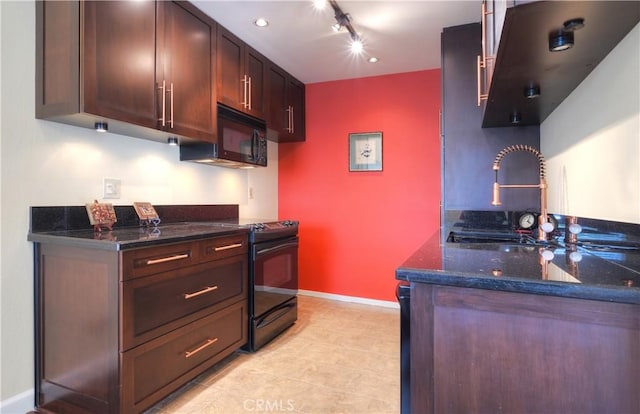 kitchen featuring track lighting, baseboards, dark stone countertops, black appliances, and a sink