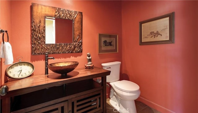 half bathroom featuring baseboards, vanity, toilet, and tile patterned floors