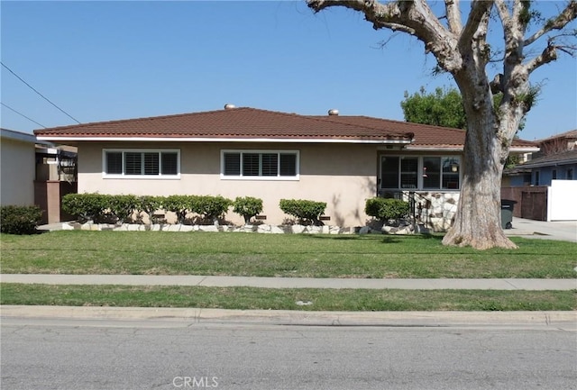 view of front of home with a tiled roof, a front lawn, and stucco siding