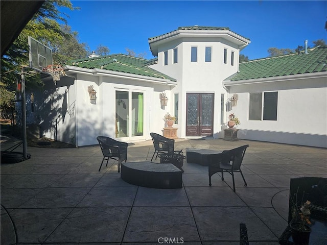 back of property with stucco siding, a tile roof, a patio, and french doors