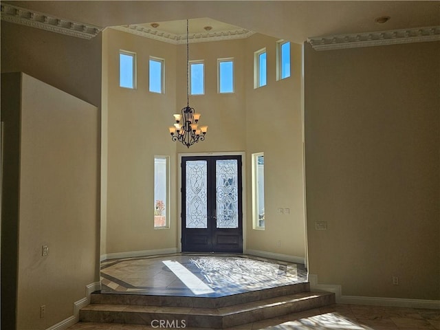 foyer entrance with a towering ceiling, an inviting chandelier, baseboards, and french doors