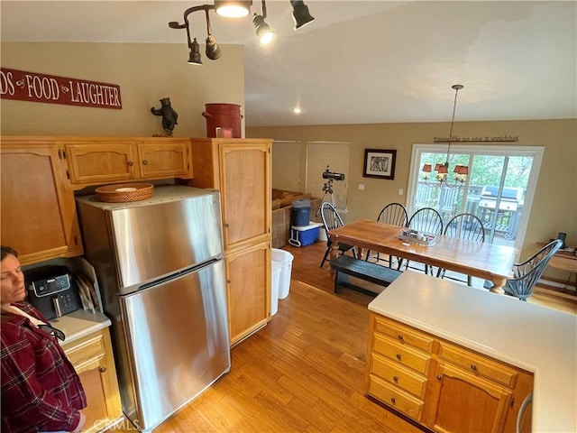 kitchen with light wood finished floors, light countertops, freestanding refrigerator, and vaulted ceiling