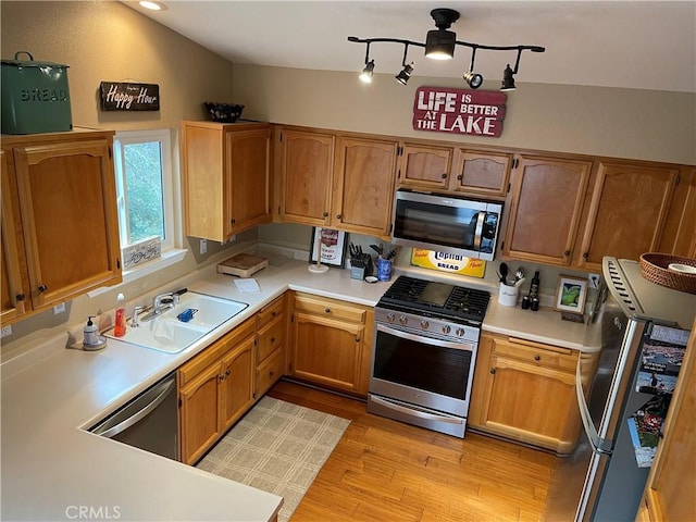 kitchen featuring a sink, appliances with stainless steel finishes, light countertops, and light wood finished floors