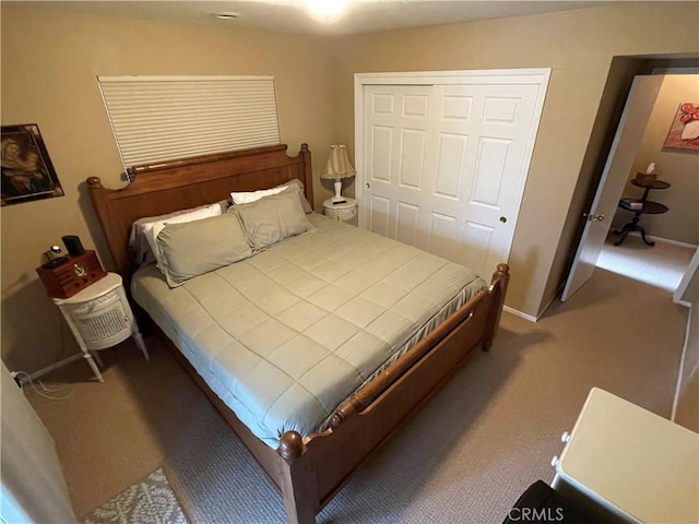 carpeted bedroom with a closet and baseboards