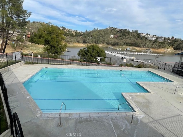 pool featuring a patio, fence, and a water view