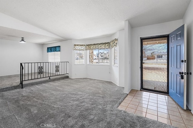 carpeted foyer featuring a textured ceiling and tile patterned flooring