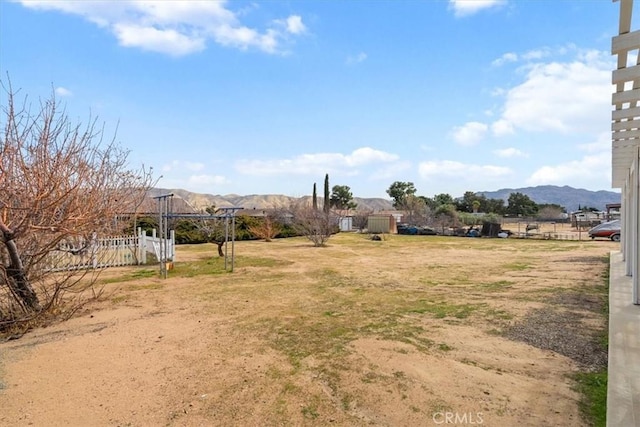 view of yard with fence, a mountain view, and a rural view