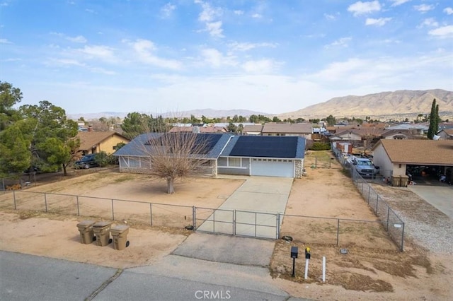 view of front facade featuring concrete driveway, a fenced front yard, solar panels, and a gate