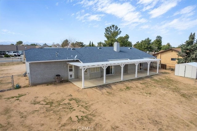 rear view of house featuring a patio, an outbuilding, fence, a storage unit, and a pergola