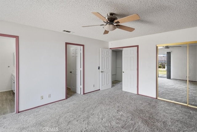 unfurnished bedroom featuring a ceiling fan, carpet, a textured ceiling, and two closets