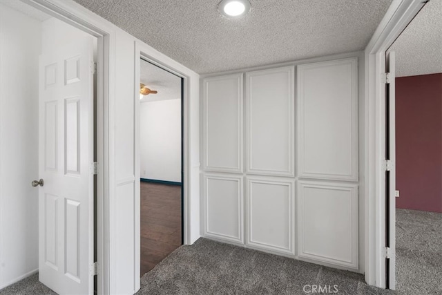 hallway with a textured ceiling and carpet flooring