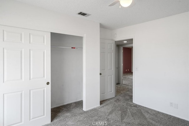 unfurnished bedroom with a textured ceiling, a closet, carpet, and visible vents