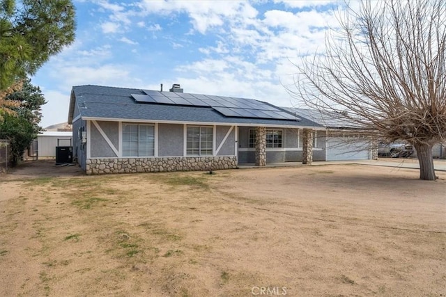 view of front facade with stucco siding, an attached garage, cooling unit, stone siding, and driveway