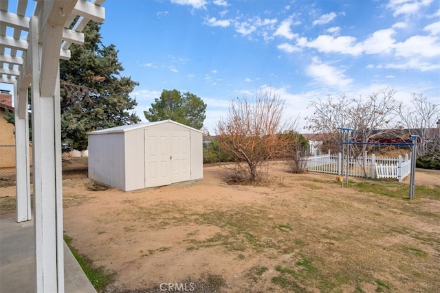 view of yard with a shed, fence, a pergola, and an outbuilding