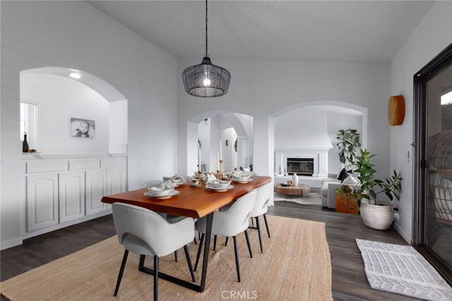 dining area with dark wood-style floors, baseboards, and a glass covered fireplace