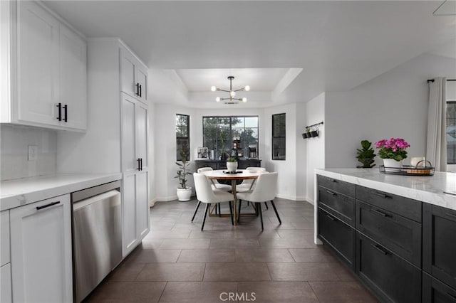 dining room featuring baseboards, a raised ceiling, and an inviting chandelier