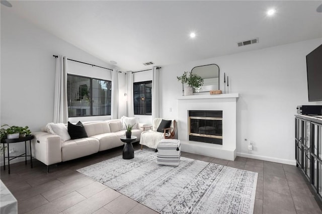 living area with recessed lighting, visible vents, vaulted ceiling, and a glass covered fireplace