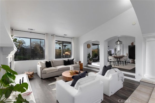 living room featuring arched walkways, wood finished floors, visible vents, and ornate columns