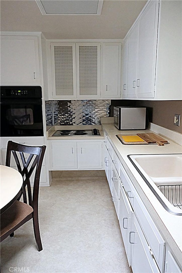 kitchen featuring black appliances, light countertops, white cabinetry, and decorative backsplash