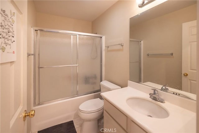 bathroom with enclosed tub / shower combo, vanity, and toilet