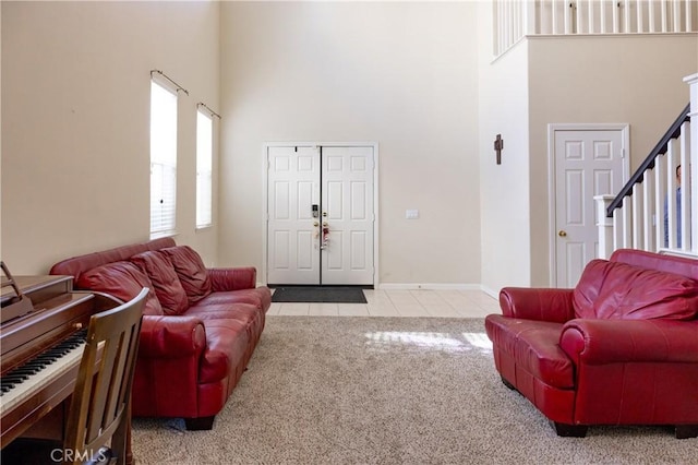 carpeted living area featuring baseboards, stairway, a high ceiling, and tile patterned floors