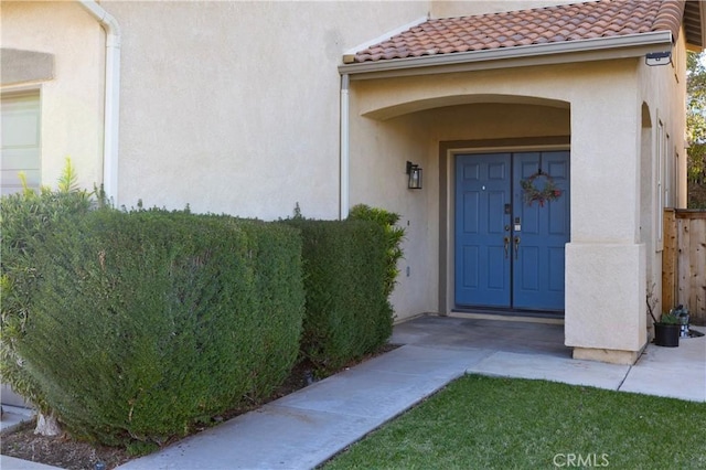 view of exterior entry with a tiled roof and stucco siding