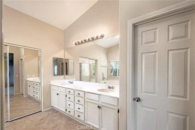 bathroom with lofted ceiling, double vanity, a sink, and tile patterned floors