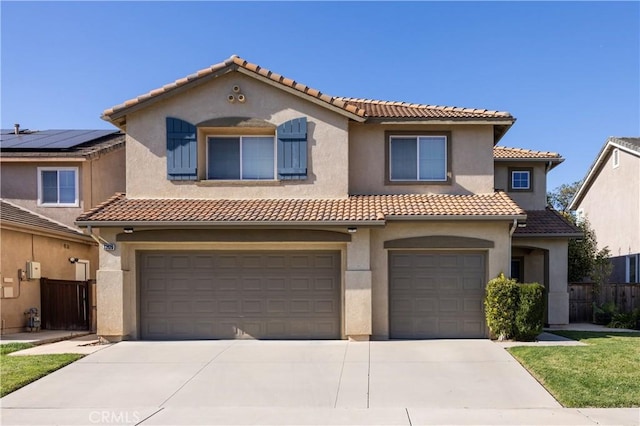 mediterranean / spanish-style home with concrete driveway, a tiled roof, an attached garage, fence, and stucco siding