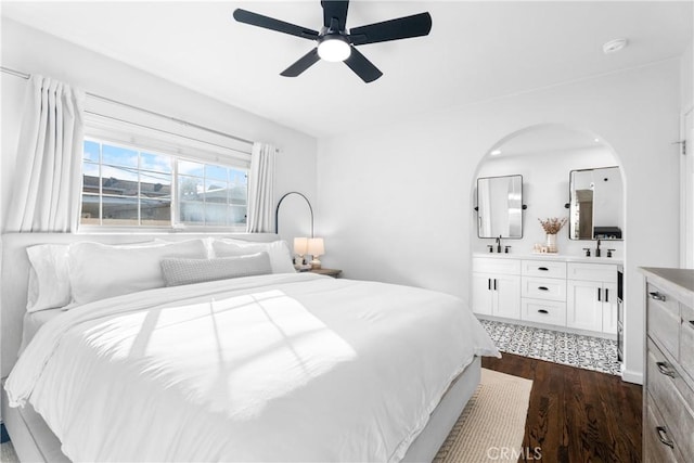 bedroom featuring ceiling fan, dark wood-style flooring, ensuite bathroom, and a sink