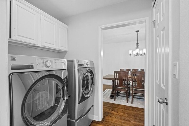 laundry room with baseboards, washing machine and clothes dryer, an inviting chandelier, cabinet space, and dark wood-style flooring