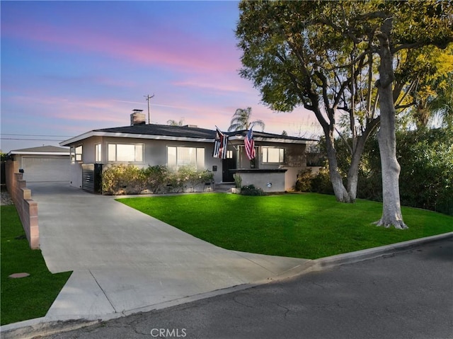 ranch-style house with stucco siding, a lawn, and an outdoor structure