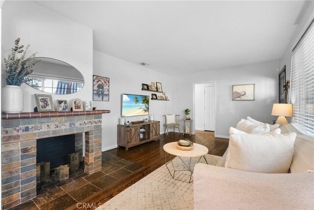 living area with a fireplace, wood finished floors, and baseboards