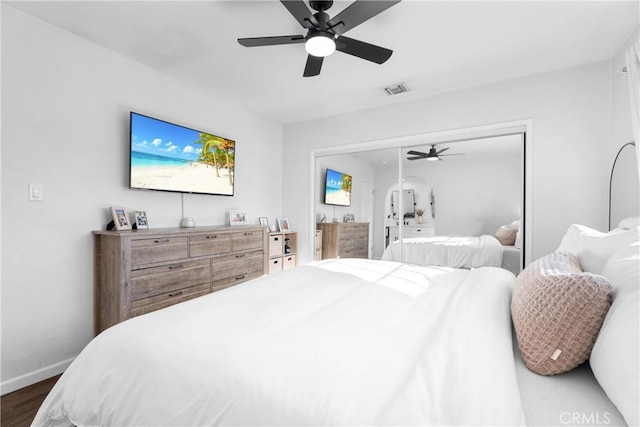 bedroom featuring visible vents, a ceiling fan, dark wood finished floors, a closet, and baseboards