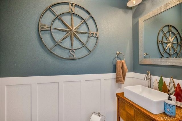 bathroom with a wainscoted wall, a decorative wall, and vanity