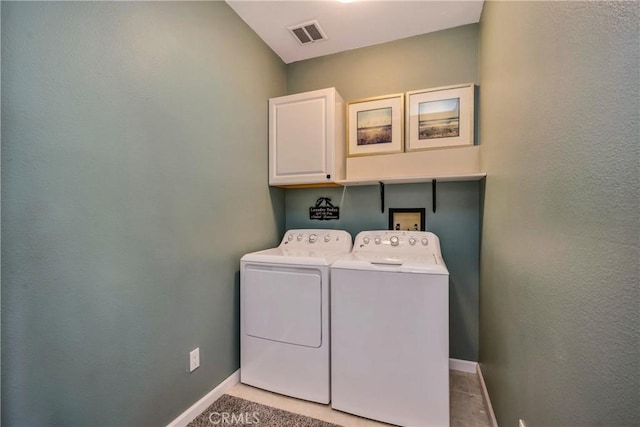 clothes washing area featuring visible vents, baseboards, cabinet space, and washer and dryer