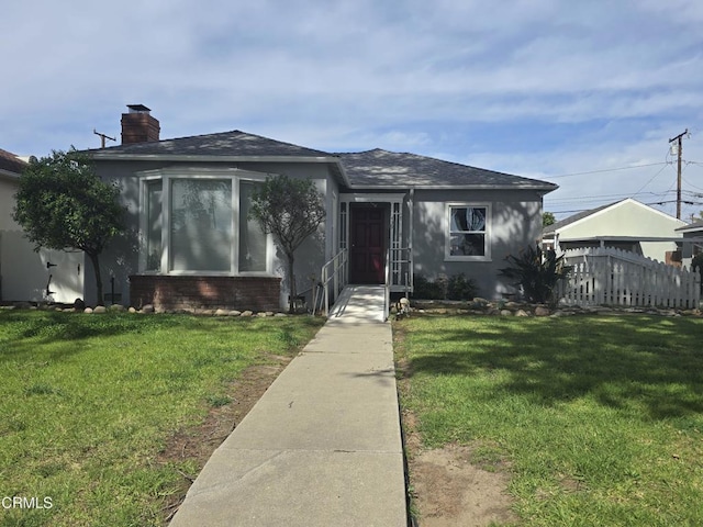 bungalow featuring brick siding, roof with shingles, stucco siding, a front lawn, and a chimney