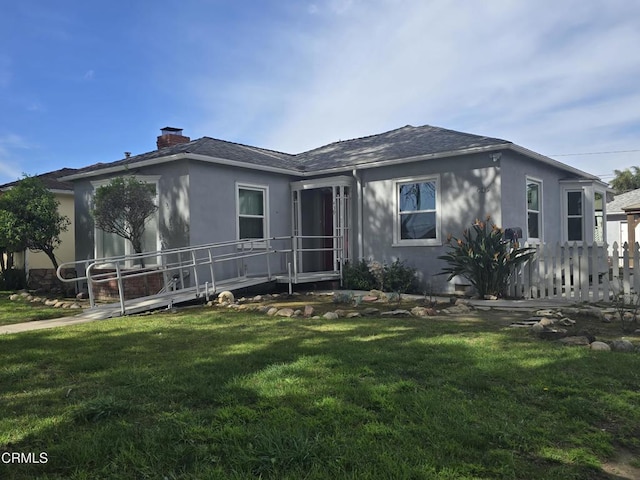 view of front of property with roof with shingles, a front lawn, a chimney, and stucco siding