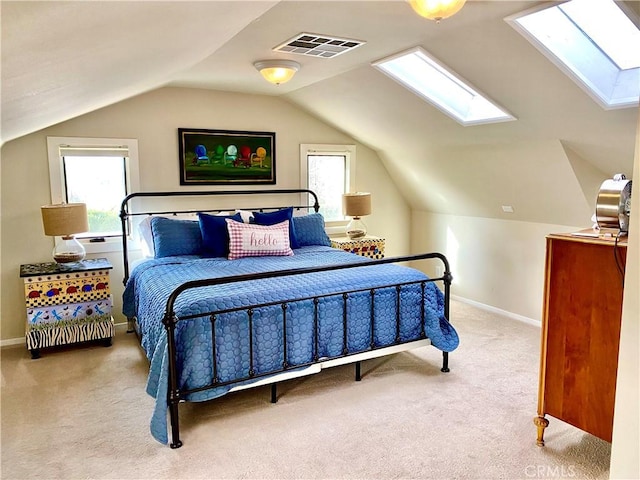 carpeted bedroom with vaulted ceiling with skylight, baseboards, and visible vents