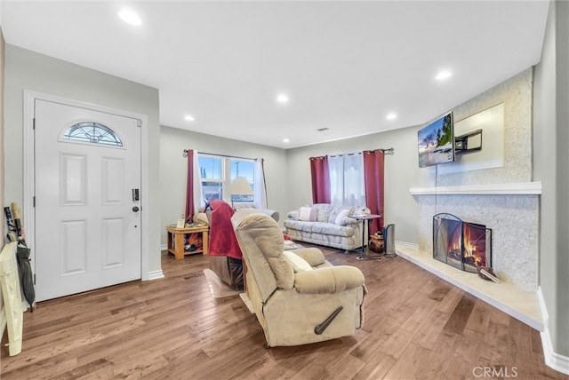 living room with baseboards, a stone fireplace, wood finished floors, and recessed lighting