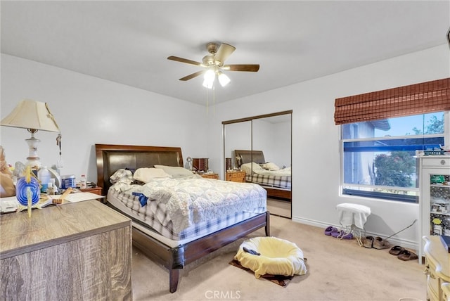 bedroom featuring light carpet, a ceiling fan, baseboards, and a closet