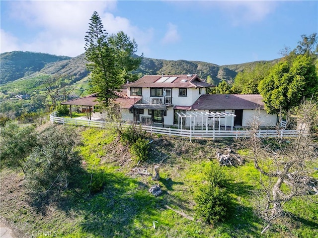 back of property featuring fence, a mountain view, and solar panels