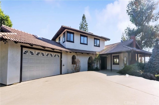 view of front of home with a garage, driveway, a tile roof, and stucco siding