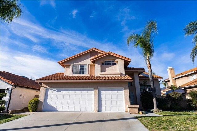 mediterranean / spanish-style house with a tile roof, an attached garage, driveway, and stucco siding
