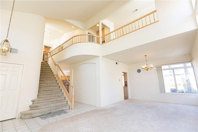 staircase featuring visible vents, carpet floors, a notable chandelier, and a high ceiling