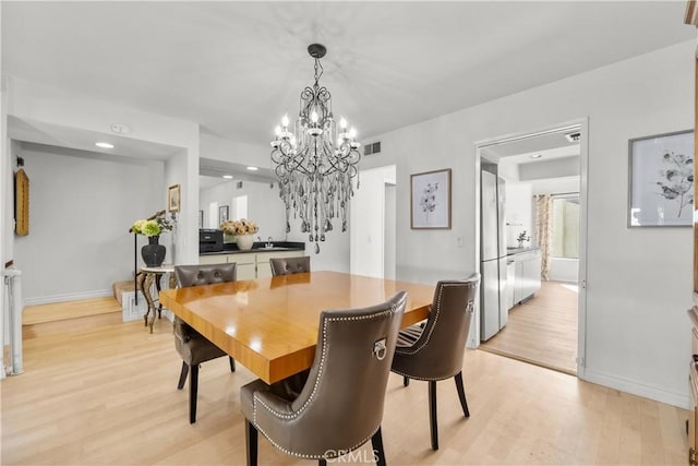 dining area featuring light wood-style floors, visible vents, baseboards, and a notable chandelier