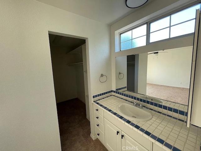 bathroom featuring tasteful backsplash, a walk in closet, and vanity