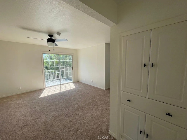 carpeted spare room with a textured ceiling, ceiling fan, and baseboards