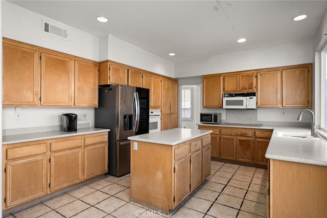 kitchen featuring visible vents, a kitchen island, appliances with stainless steel finishes, light countertops, and a sink