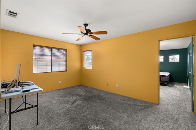 carpeted office space featuring visible vents and a ceiling fan