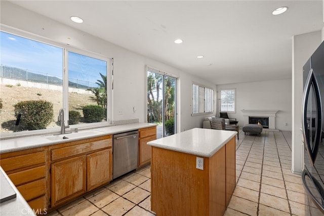 kitchen featuring a sink, freestanding refrigerator, a center island, dishwasher, and a glass covered fireplace